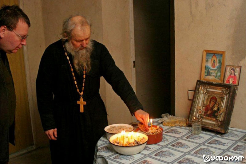 Отец Савелий достает Владимиру Шаку из импровизированного подсвечника фрагмент застывшего в песке вещества красноватого цвета. Фото Сергея Томко.